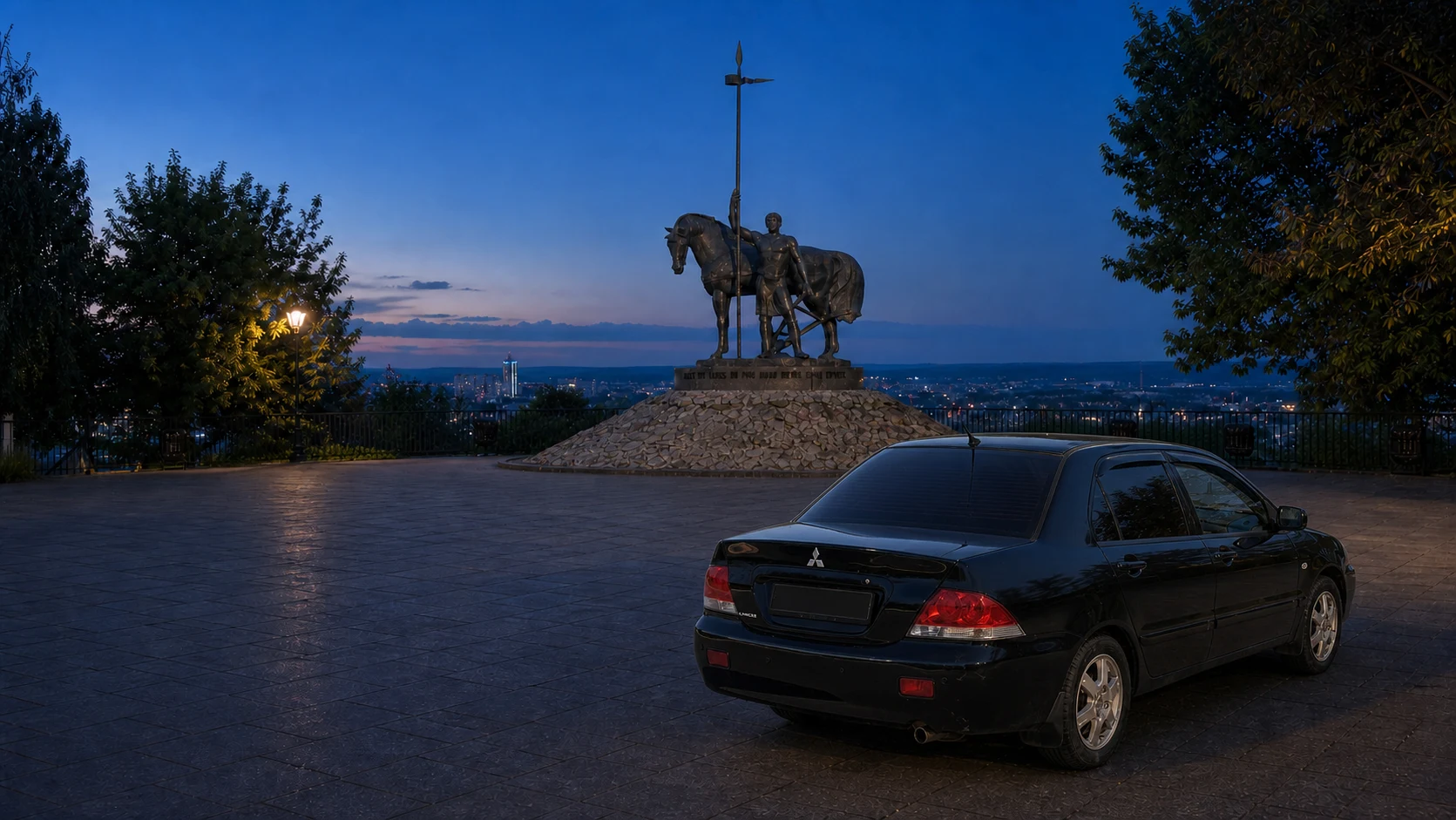 Чёрный Mitsubishi Lancer IX сзади и справа на брусчатке у памятника Первопоселенцу в Пензе